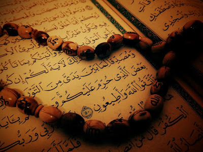 صورة قريبة لمصحف مفتوح يظهر آيات قرآنية، وسبحة موضوعة عليه بشكل جميل، رمز للقراءة والذكر بعد الصلاة